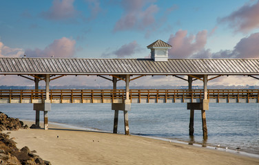 Sticker - An old wood and concrete pier over empty beach