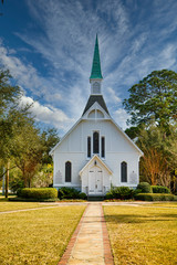 Sticker - A small white, wooden church down sidewalk under nice sky