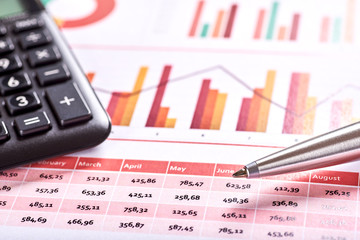 Photo of orange financial and planning chart with black calculator and silver pen.