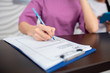© zinkevych - Receptionist wearing purple uniform holding pen while making notes