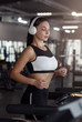 © Prostock-studio - Pretty girl with headphones jogging on treadmill in gym