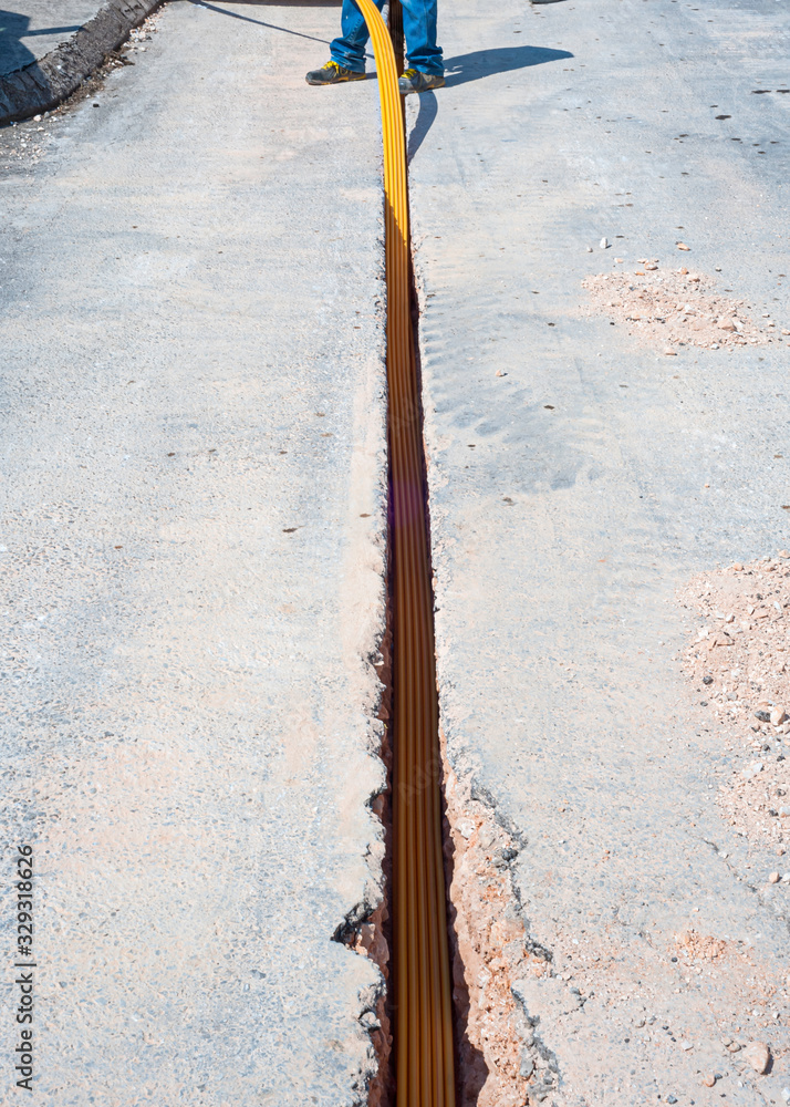 Worker inserts fiber optic cables buried in a micro trench Stock Photo ...