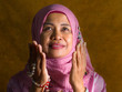 © TheVisualsYouNeed - isolated studio portrait of happy and positive senior muslim woman in her 50s wearing traditional Islam hijab head scarf praying in Islamic culture and religion concept