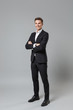 © ViDi Studio - Successful young business man in classic black suit shirt posing isolated on grey wall background studio portrait. Achievement career wealth business concept. Mock up copy space. Hold hands crossed.