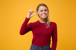 © ViDi Studio - Confused young blonde woman girl in casual clothes posing isolated on yellow orange background in studio. People lifestyle concept. Mock up copy space. Gesturing demonstrating size with workspace.