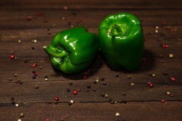 Two bell green peppers on a wooden background