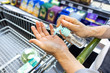 Asian shopper disinfecting hands with sanitizer in supermarket during shopping