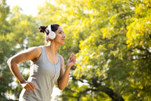 Sportswoman Listening Music And Jogging At Park