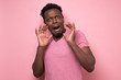 © Viktor Koldunov - Funny african american scared man in pink shirt with worried expression. Studio shot on colored wall.