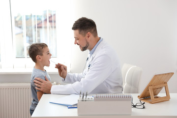 Wall Mural - Children's doctor examining little patient's throat in clinic