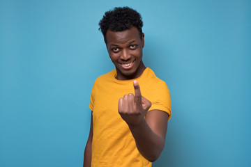 Canvas Print - African american young man shoeing coming gesture. Come here. Studio shot on blue wall.