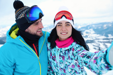 Canvas Print - Young couple taking selfie at mountain resort. Winter vacation