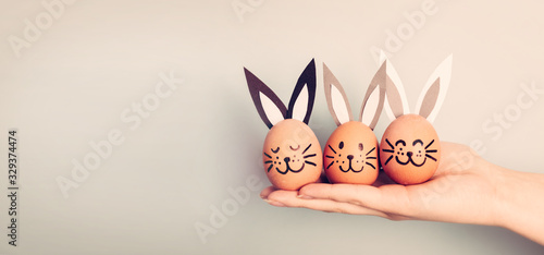 Fotomural Three painted smiling Easter eggs bunnies on woman's hand