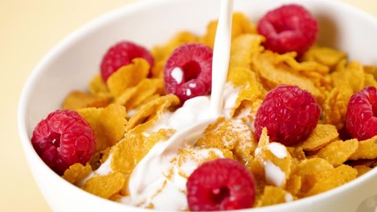 Poster - bowl of cornflakes with raspberries and pouring milk, slow motion