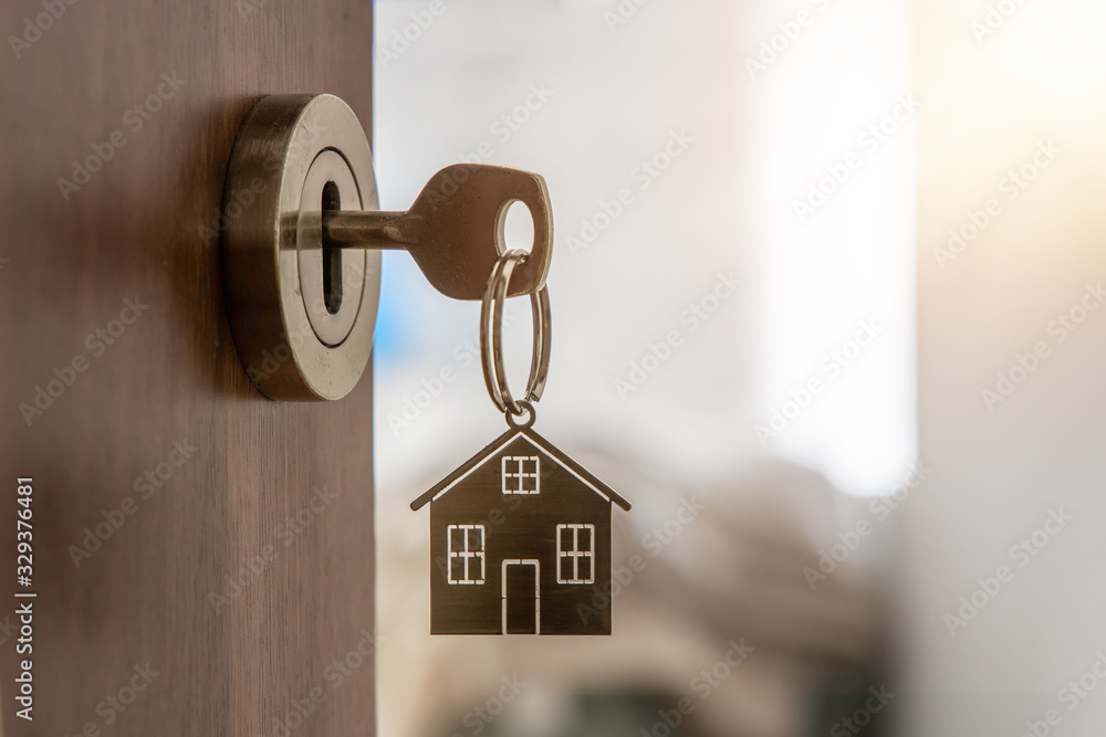 Open door to a new home with key and home shaped keychain. Mortgage, investment, real estate, property and new home concept - obrazy, fototapety, plakaty 