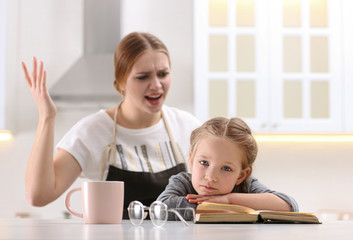 Wall Mural - Mother scolding her daughter while helping with homework in kitchen