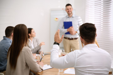 Wall Mural - Young man raising hand to ask question at business training in conference room