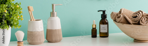 Fotografía Panoramic view of flowerpot, cosmetic and hygiene products near bowl with towels