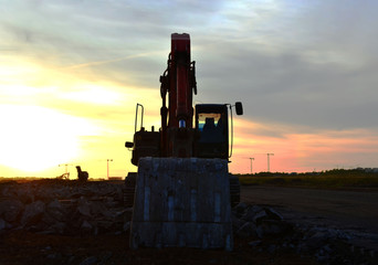 Poster - Large tracked excavator on a construction site on the awesome sunset background. Road repair, asphalt replacement. Digging the ground for the foundation and construction of a new building.