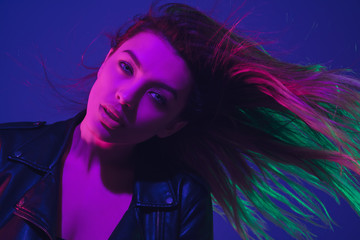 Dancing, hairs flying. Caucasian woman's portrait isolated on blue studio background in neon light. Beautiful female model. Concept of human emotions, facial expression, sales, ad. Trendy colors.