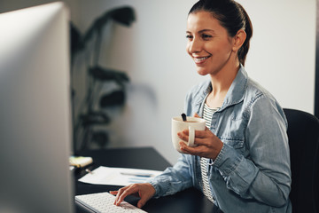 Smiling businesswoman working at her desk and drinking tea