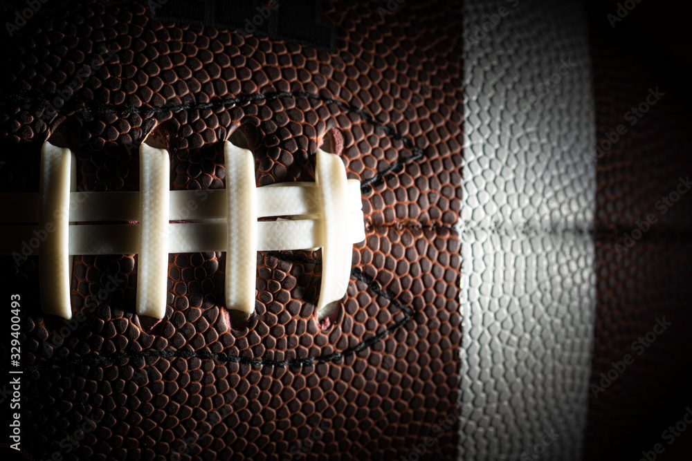 Close-up of an American football on black background - obrazy, fototapety, plakaty 