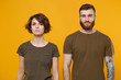 © ViDi Studio - Serious young couple two friends guy girl in casual t-shirts posing isolated on yellow orange wall background studio portrait. People emotions lifestyle concept. Mock up copy space. Looking camera.