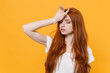 © ViDi Studio - Exhausted young redhead woman girl in white blank empty t-shirt posing isolated on yellow background in studio. People lifestyle concept. Mock up copy space. Put hand on head, keeping eyes closed.