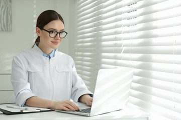 Sticker - Young female doctor working with laptop at table in office