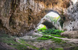 Devetashka cave interior, near Lovech town, Bulgaria. Panorama of entrance tunnel with hole on top and deep green grass