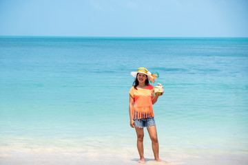 Wall Mural - Happy Asian woman, a sexy Thai lady, drinking coconut water at turquoise sea  during  holidays  trip outdoors at natural ocean at island , Thailand.