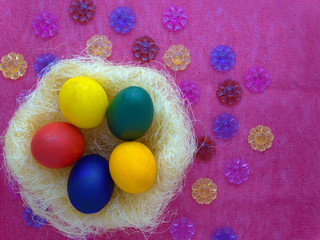 Colorful Easter eggs in a nest on a pink background with flowers