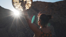 Unrecognizable Woman Playing Tambourine In Sun Glare In Mountains Sunset.