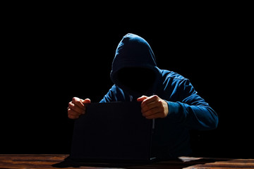 Hacker with laptop at the table breaks into the system