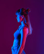 © insta_photos - Fashion beauty young blond hair 20s girl model profile side view stand at purple studio background, sexy trendy stylish woman pretty face in neon blue party night light concept, vertical photo.