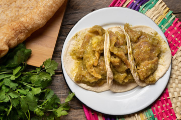 Mexican pork chicharron with green sauce tacos on wooden background