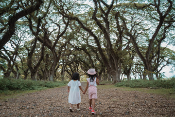 two children walk away between a shady tree full of mystery