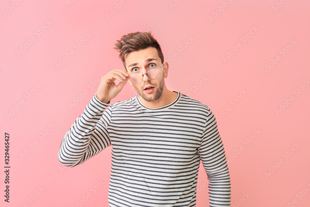 Surprised man with stylish eyeglasses on color background
