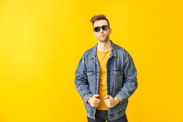 Young man with stylish sunglasses on color background