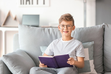 Poster - Little boy wearing glasses while reading book at home