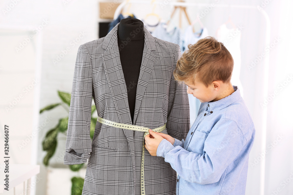 Cute little tailor near mannequin in atelier