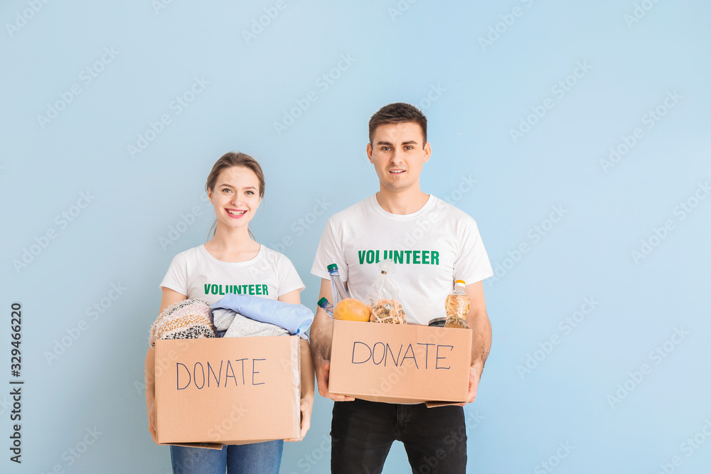 Volunteers with donations for poor people on color background
