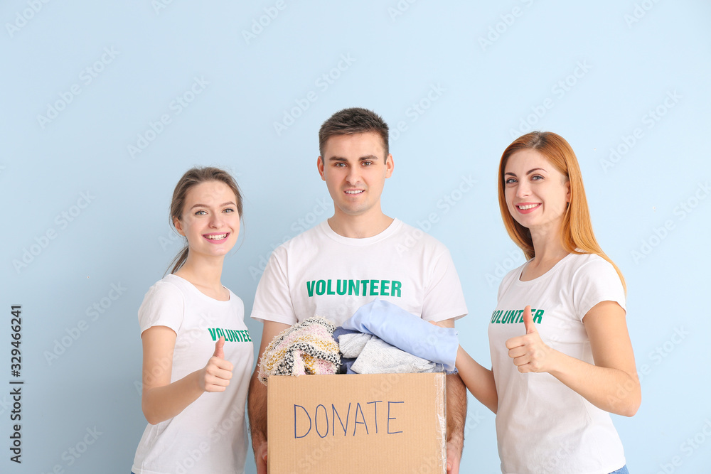 Volunteers with donations for poor people on color background