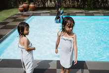 Two Asian Little Girls Stand Wearing Towels After They Finish Playing In The Pool