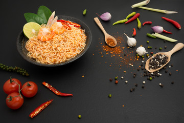 Poster - Instant noodles, spicy hot and spicy shrimp soup with Thai spices put on the table in the kitchen, black background