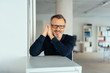 © contrastwerkstatt - Relaxed friendly man leaning on an office cabinet