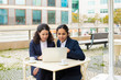 © Mangostar - Businesswomen with laptop in outdoor cafe. Focused female colleagues sitting at table, drinking coffee and using laptop computer in outdoor cafe. Wireless technology concept