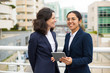 © Mangostar - Happy businesswomen with digital tablet. Cheerful professional female colleagues standing with digital tablet on urban city street. Wireless technology concept