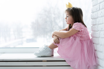 Cute little girl in a princess costume. Pretty child preparing for a costume party. Beautiful queen in gold crown.