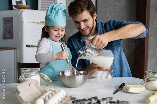 Cuadros en Lienzo Daddy with daughter baking cake together in home kitchen.